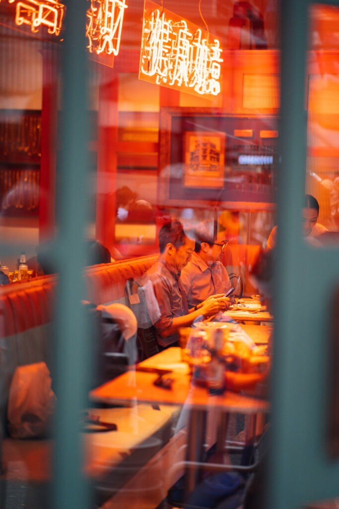 Spiegelungen in einem Fenster. Person beim essen fotografiert mit einer langen brennweite von stefan sperl