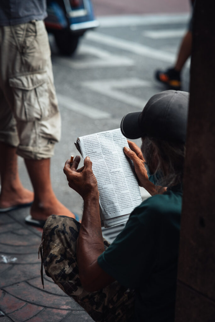 Man liest zeitung auf der Straße von Bangkok. in der linken hand hält er eine zigarette | fotograf stefan sperl fotografiert mit einer langen brennweite von stefan sperl