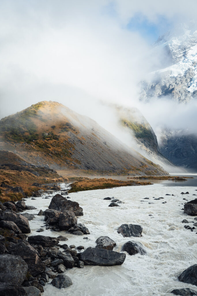 Wolkenverhangen im dichten Nebelhängende Berge. Wanderer stehen vor einem see. Fotografiert von Stefan Sperl