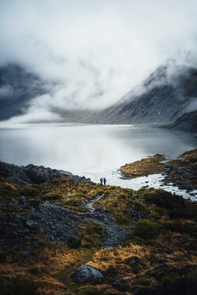 Wolkenverhangen im dichten Nebelhängende Berge. Wanderer stehen vor einem see. Fotografiert von Stefan Sperl